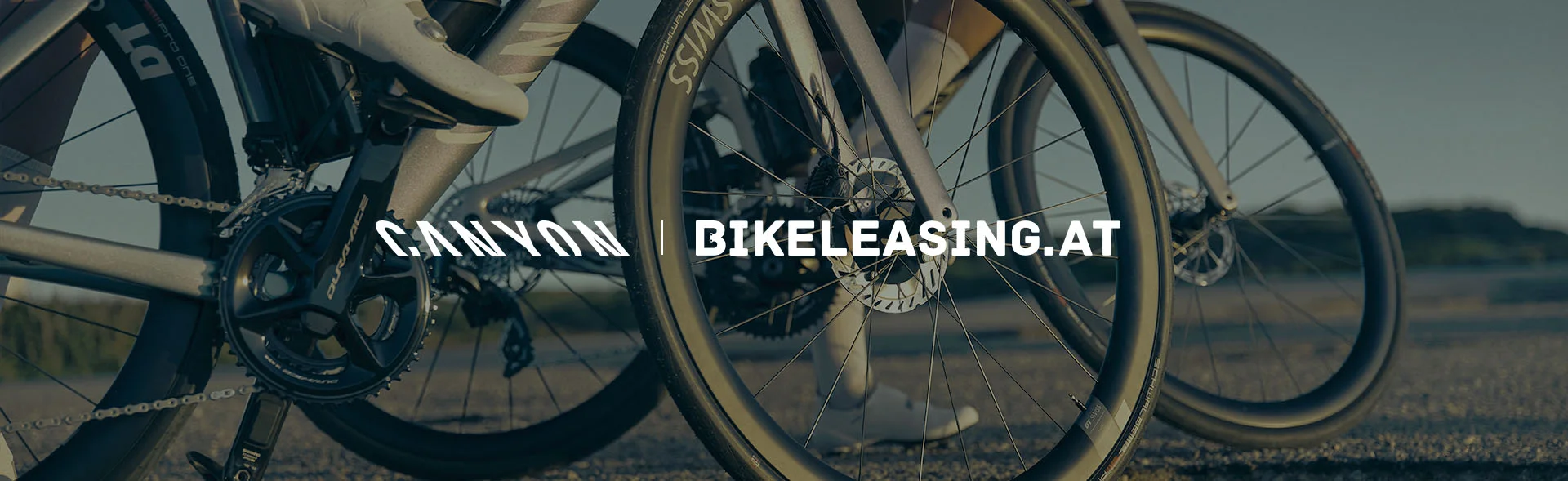 Nahaufnahme mehrerer Fahrradlaufräder und Antrieb auf einer Straße; mittig ist der Schriftzug „CANYON | BIKELEASING.AT“ eingeblendet.