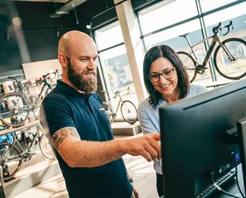 Radhändler im Gespräch mit Kundin vor PC