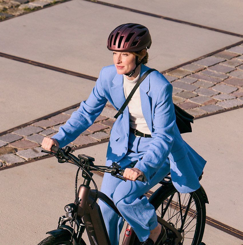 Frau in blauem Businessanzug auf Dienstrad
