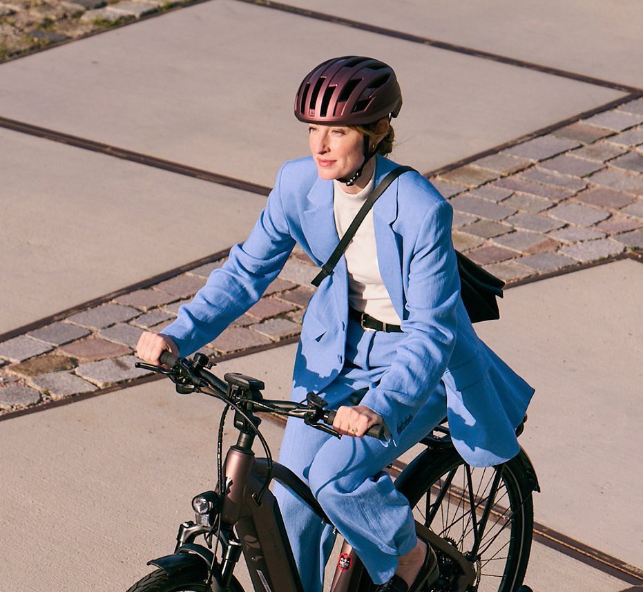 Frau in blauem Businessanzug auf Dienstrad