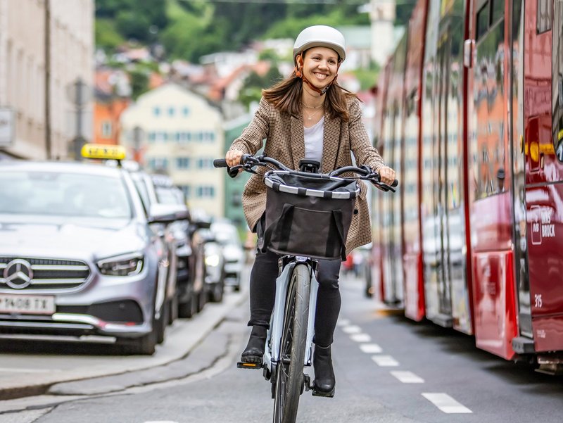 Frau fährt mit Fahrrad auf Radweg zwischen Autos und Straßenbahn durch