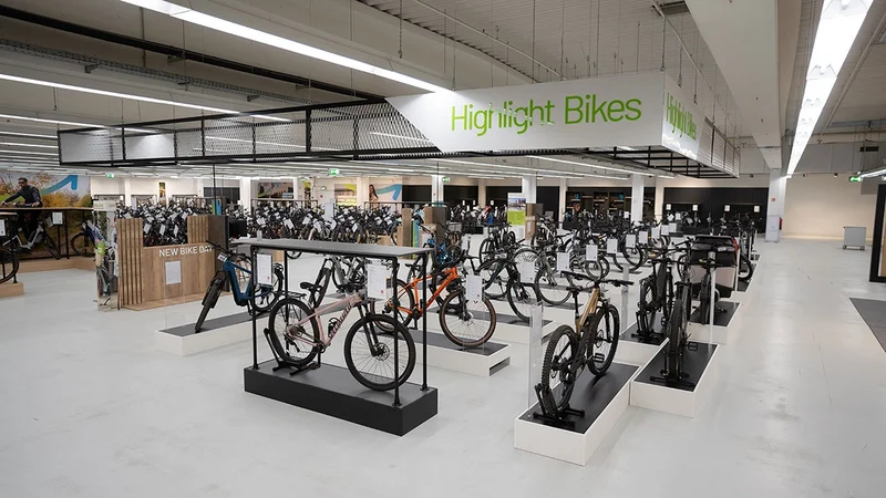 Großer Fahrrad-Showroom mit ausgestellten Fahrrädern und E-Bikes in einer modernen Verkaufsfläche. Über dem Ausstellungsbereich hängt ein Schild mit der Aufschrift ‚Highlight Bikes‘.