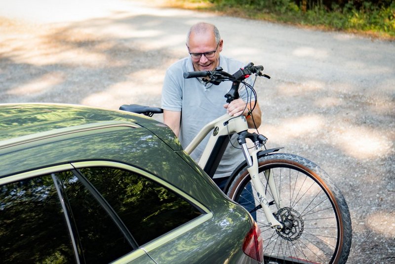 Mann belädt Radträger mit E-Bike