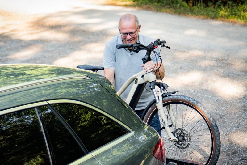 Mann belädt Radträger mit E-Bike