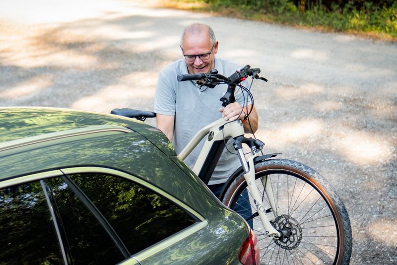 Mann belädt Radträger mit E-Bike