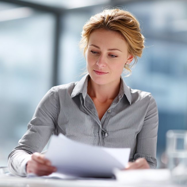 Weibliche Person betrachtet Unterlagen, die sie in der Hand hält.