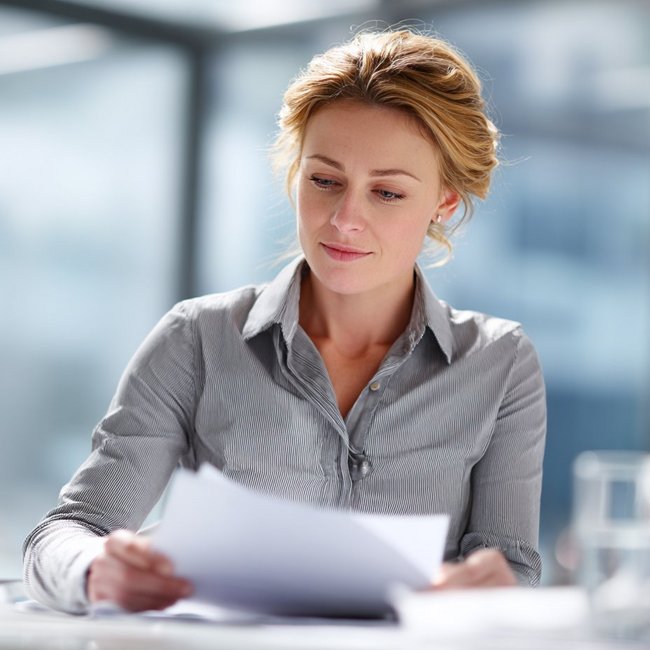 Weibliche Person betrachtet Unterlagen, die sie in der Hand hält.