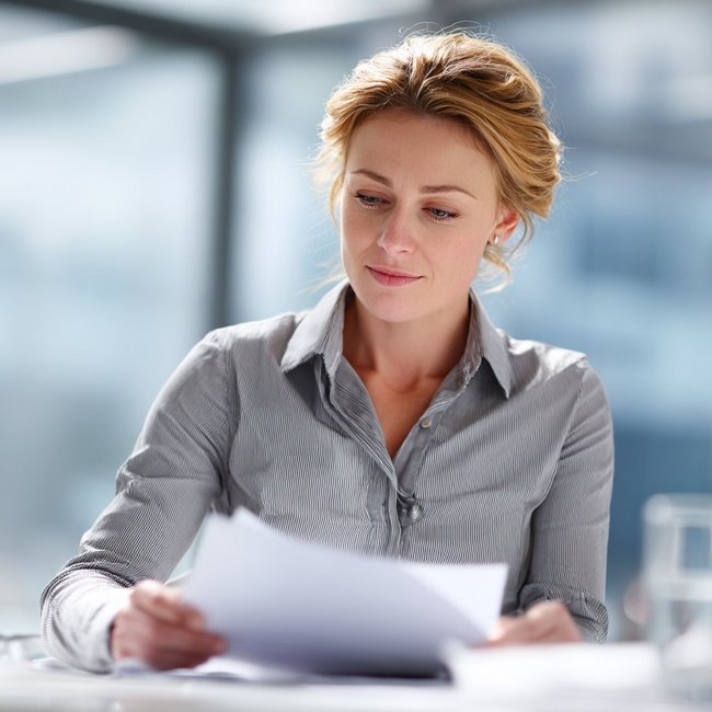 Weibliche Person betrachtet Unterlagen, die sie in der Hand hält.