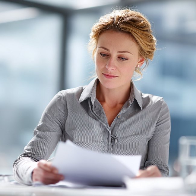 Weibliche Person betrachtet Unterlagen, die sie in der Hand hält.
