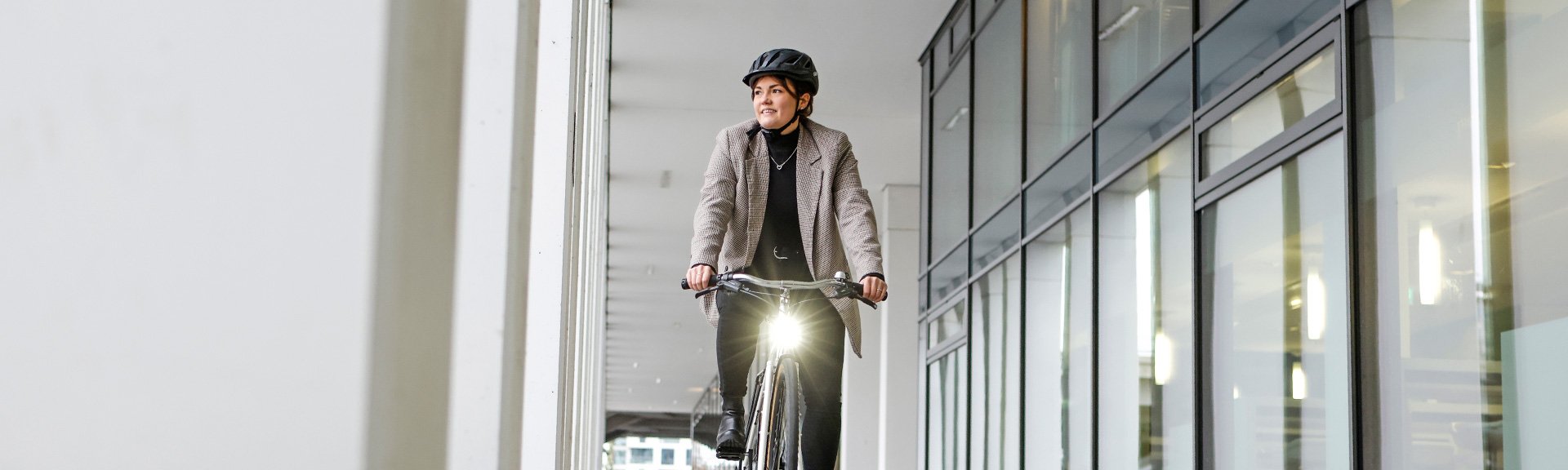 Frau mit Stadtrad neben Gebäude