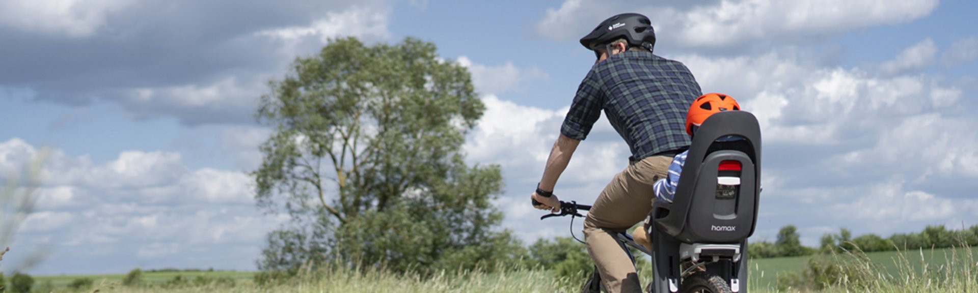 Radfahrer und Kind im Kindersitz auf Feldweg