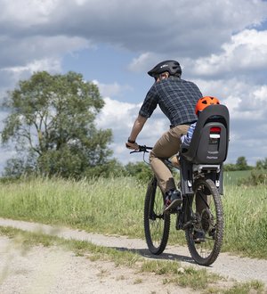 Radfahrer und Kind im Kindersitz auf Feldweg