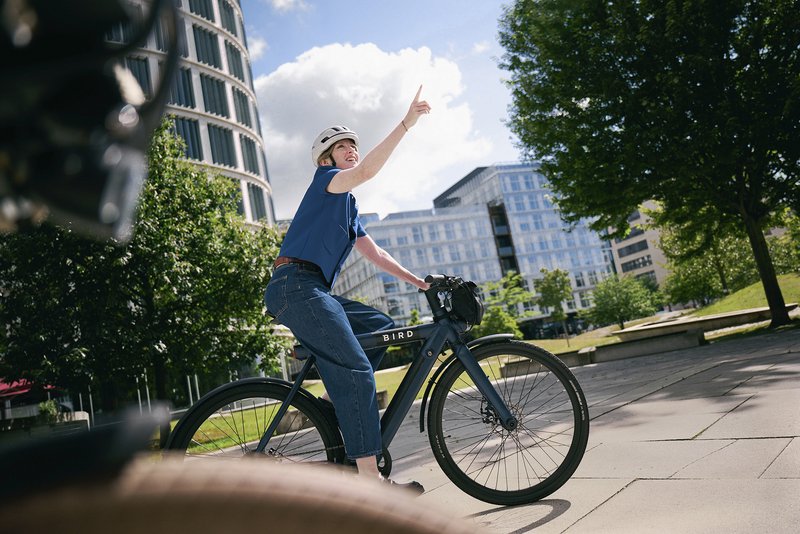 Frau auf Urban Bike zeigt nach oben 