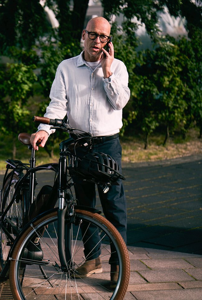 Mann mit Fahrrad steht und telefoniert