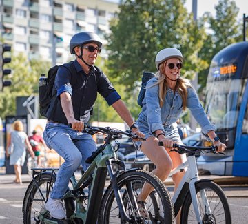 Mann und Frau auf E-Bikes in der Stadt