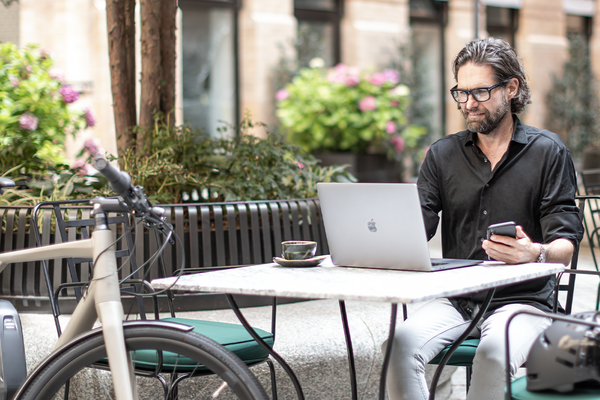 Mann sitzt in Gastgarten am Laptop