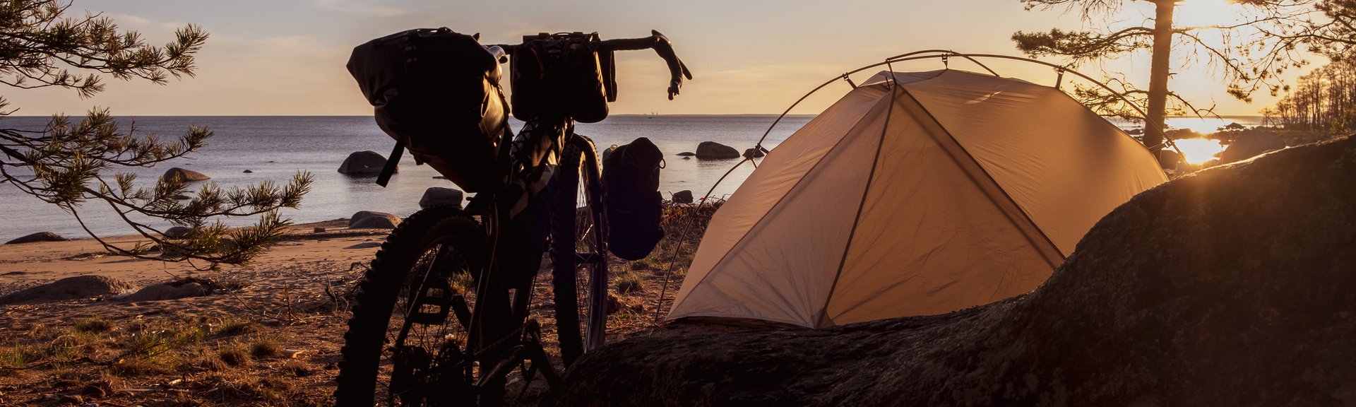 Bikepacking Tipps Gravelbike und Zelt am Strand bei Sonnenuntergang