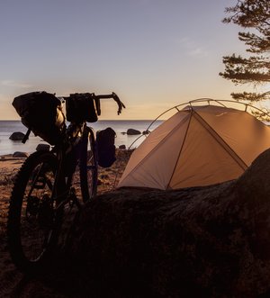 Gravelbike und Zelt am Strand bei Sonnenuntergang