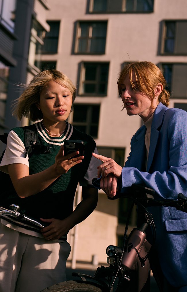 2 Frauen mit Rädern schauen auf iPhone