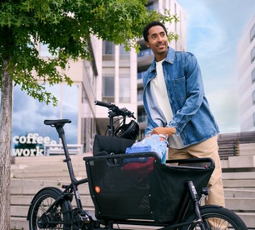 Mann in städtischer Umgebung belädt Lastenrad