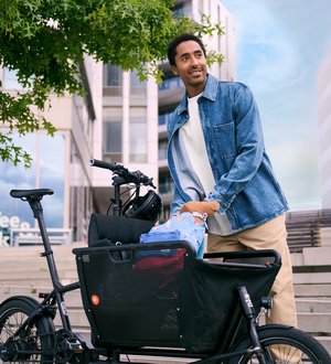 Mann in städtischer Umgebung belädt Lastenrad