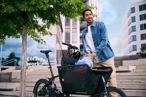 Mann in städtischer Umgebung belädt Lastenrad