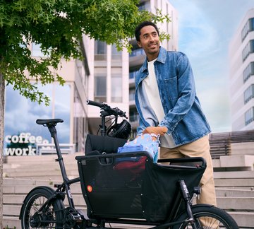 Mann in städtischer Umgebung belädt Lastenrad