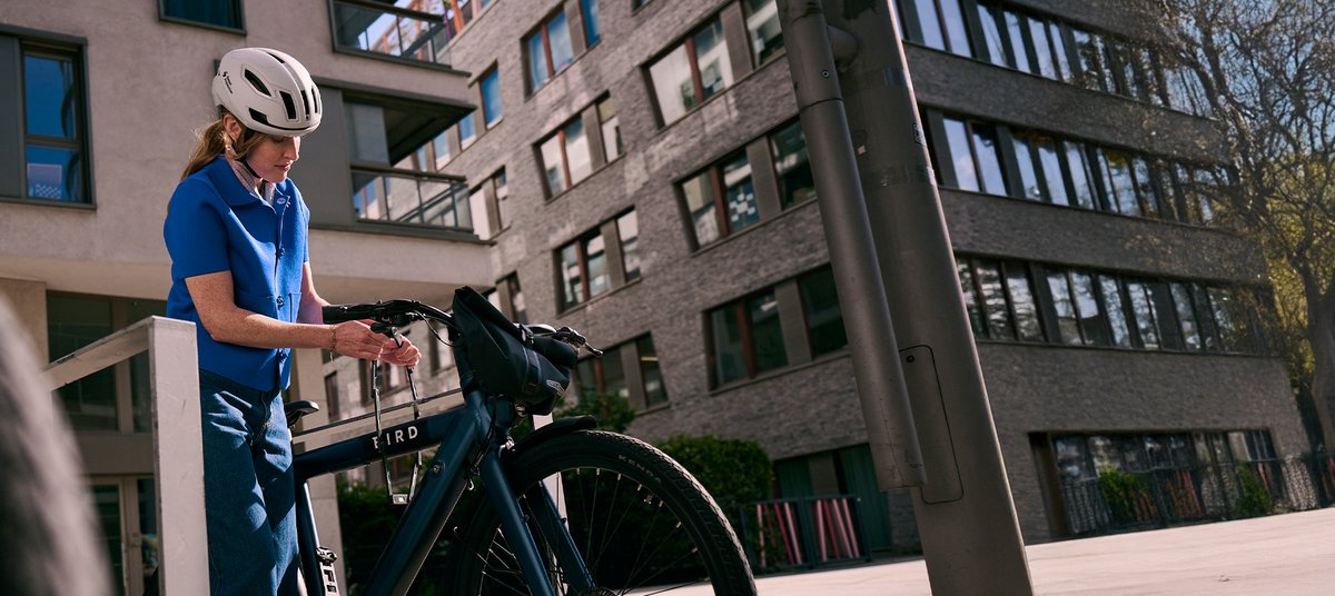 Frau kettet Stadtrad an Radbügel