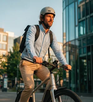 Mann in Hemd abends auf Fitnessbike in der Stadt