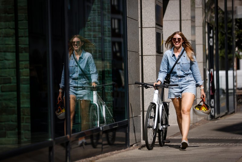 Frau in der Stadt schiebt Dienstrad