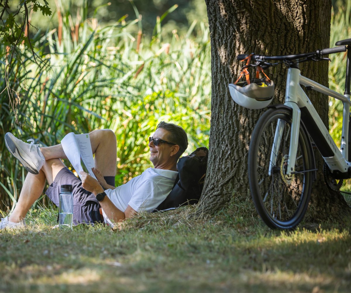 Mann mit Dienstrad und Unterlagen im Park