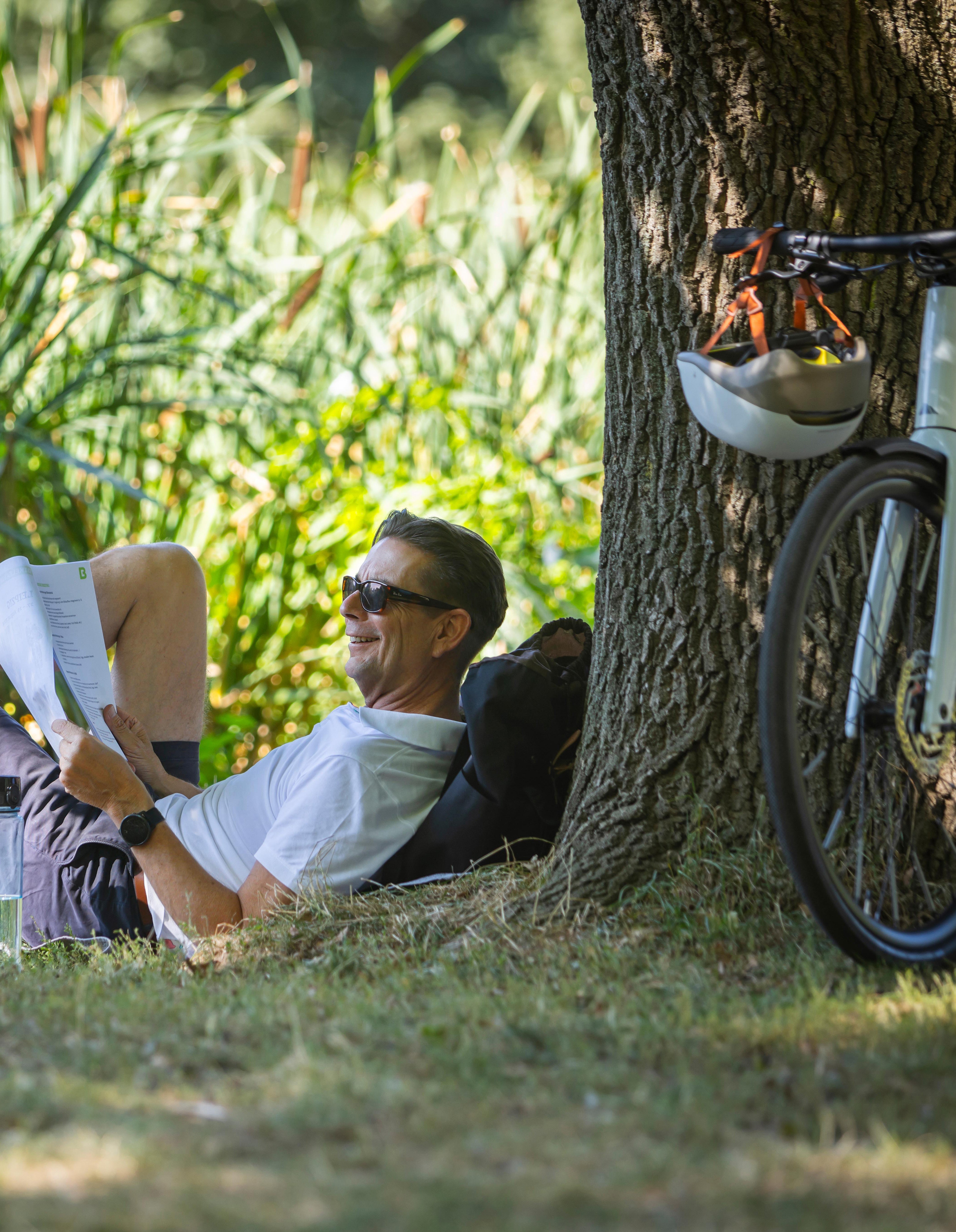 Mann mit Dienstrad und Unterlagen im Park
