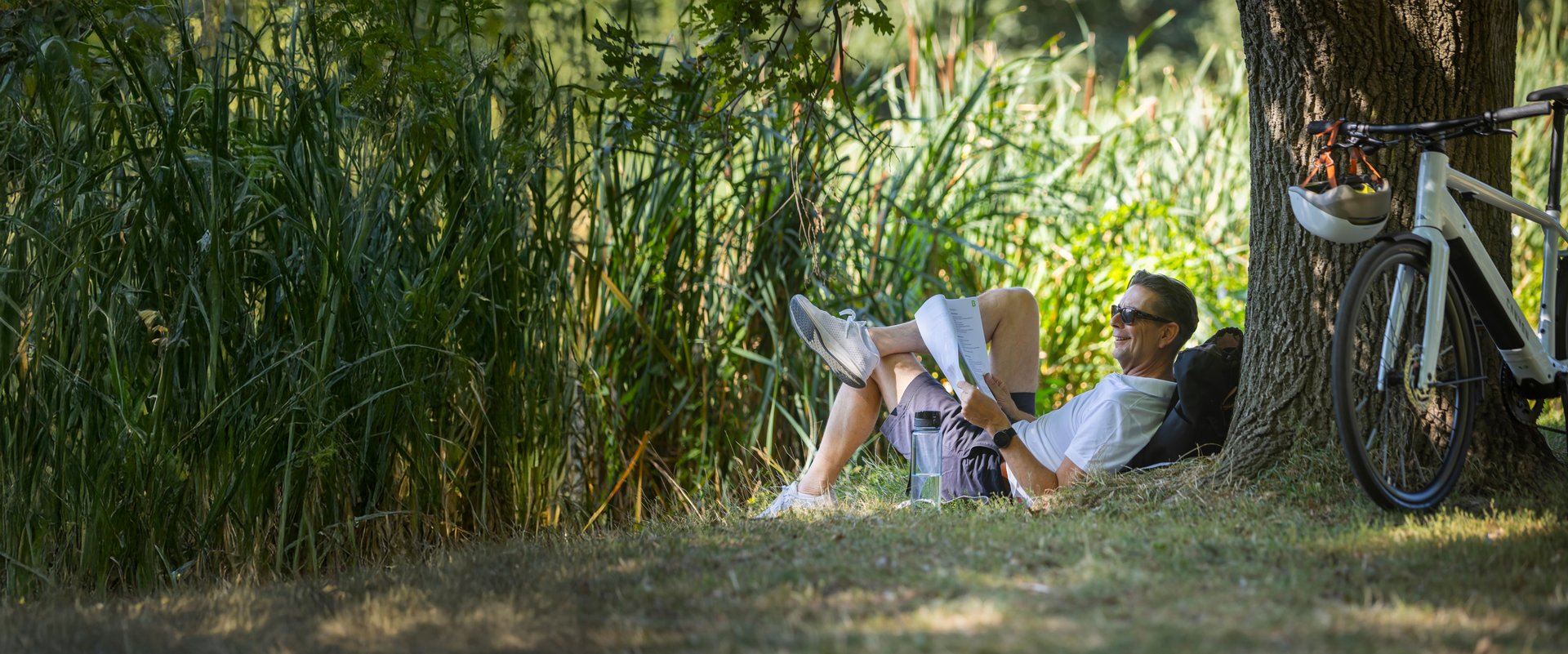 Mann mit Dienstrad und Unterlagen im Park