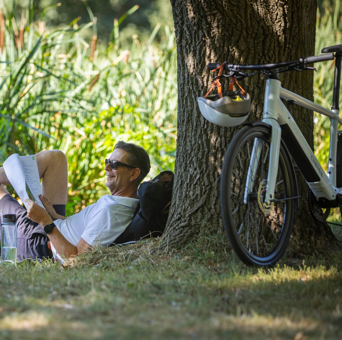 Mann mit Dienstrad und Unterlagen im Park
