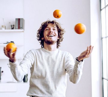 Mann jongliert mit Orangen