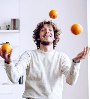 Mann jongliert mit Orangen