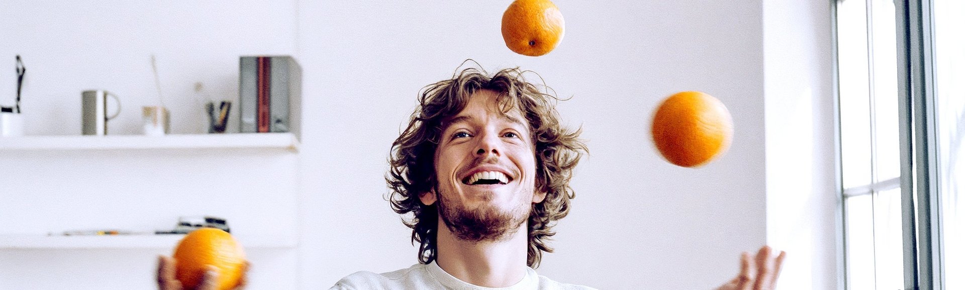 Mann jongliert mit Orangen