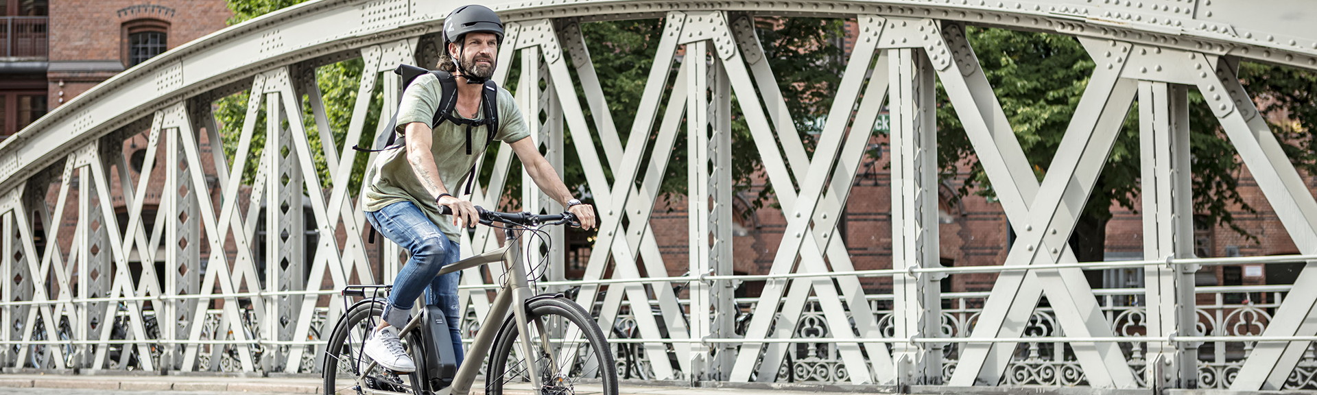 Mann mit Stadtrad auf Brücke