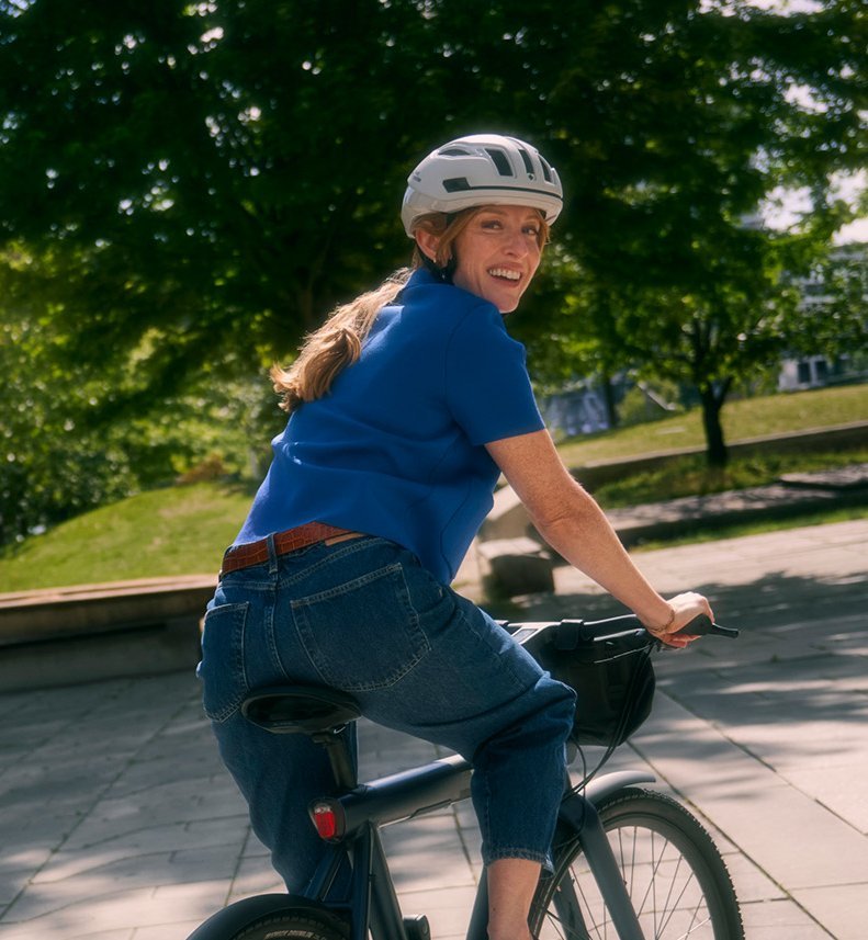 Frau auf Stadtrad blickt über die Schulter in die Kamera