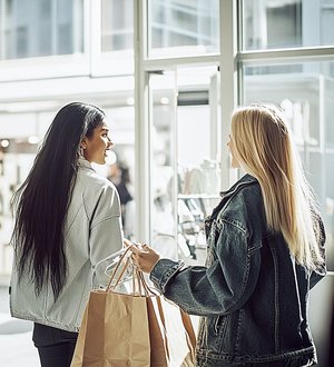 Zwei Frauen beim shoppen in einem Geschäft, beide haben Einkauftüten in der Hand