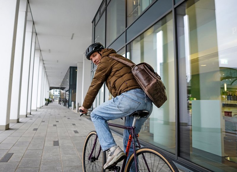 Mann mit Arbeitstasche auf Fitnessbike 