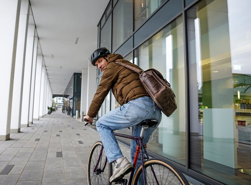 Mann mit Arbeitstasche auf Fitnessbike 