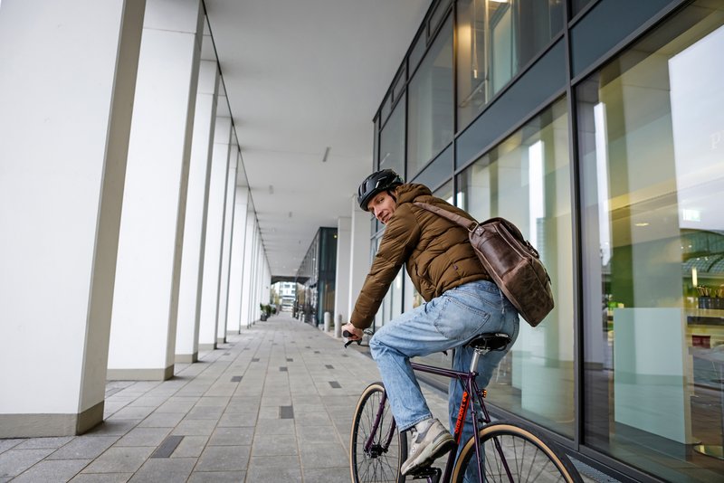Mann mit Arbeitstasche auf Fitnessbike 