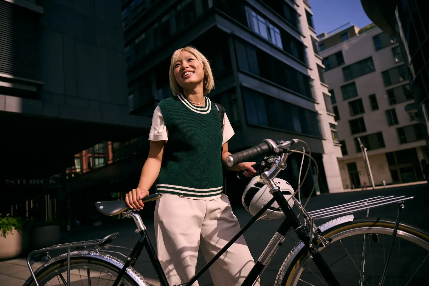 Frau steht in der Stadt neben einem Fahrrad und lächelt-
